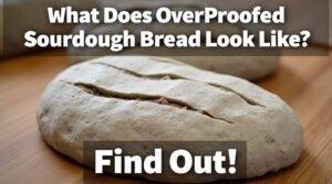 Close-up of a rustic sourdough loaf with cracked crust on a wooden surface.